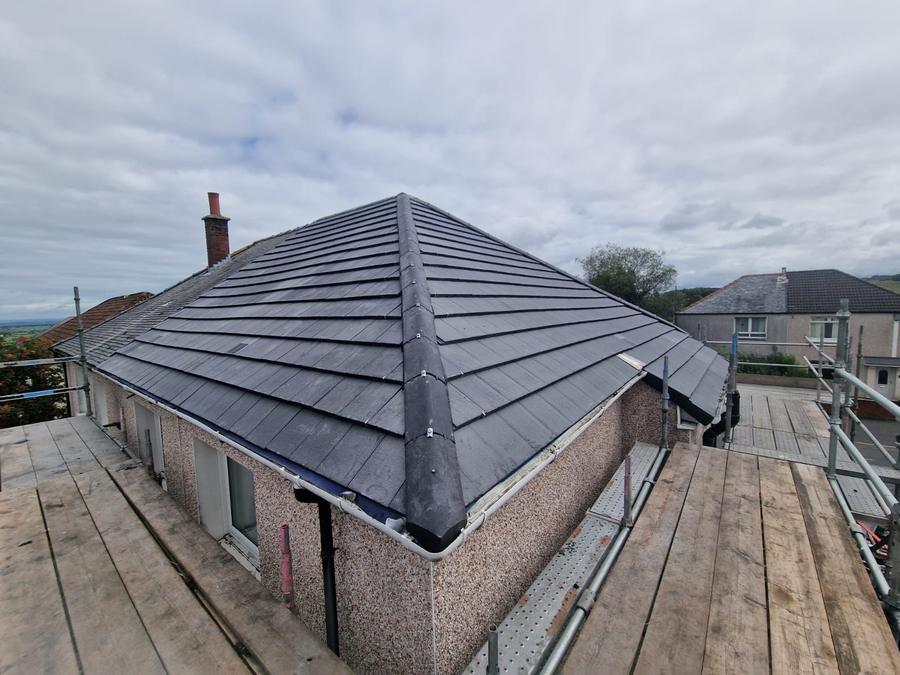 New grey tiled hip roof on a bungalow, seen from the scaffold