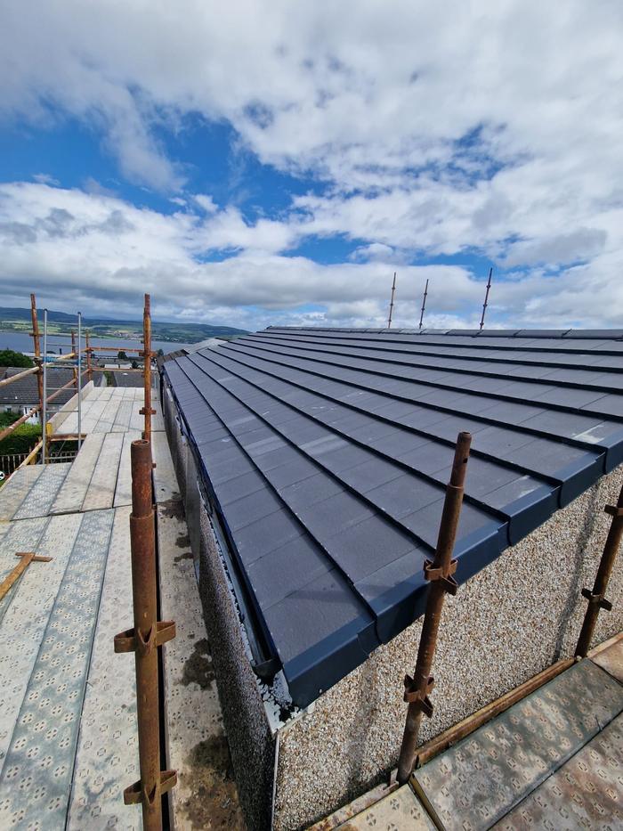 New dark grey tiles on a bungalow with the sea in the distance
